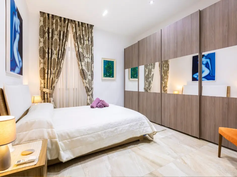 Stylish bedroom with a large wardrobe, decorative curtains, and warm lighting, representing vacation rental management services in Malta