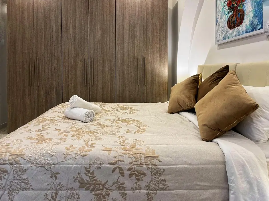 Comfortable bedroom with a large wardrobe and rolled towels, representing vacation rental management services in Malta